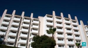 a large white building with palm trees in front of it at Mirachoro Albufeira in Albufeira