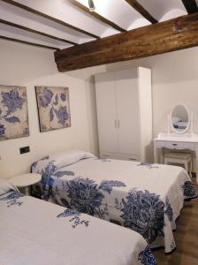 two beds in a room with white walls and wooden ceilings at Hotel La Huella Del Camino in Belorado