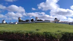 een grasheuvel met witte gebouwen en windmolens bij Cantinho da Avó in Vila do Bispo