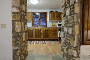 a kitchen with wooden cabinets and a stone wall at Linos Traditional Cottage in Theológos +28 photos