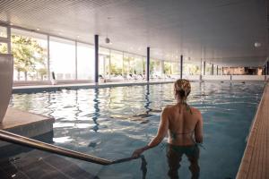 uma mulher parada na água numa piscina em Hôtel du Grand Lac Excelsior em Montreux