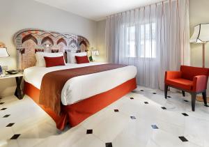 a bedroom with a large bed and a red chair at Eurostars Conquistador in Córdoba