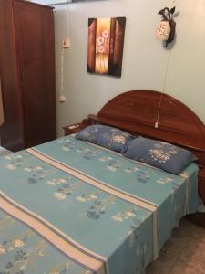 Schlafzimmer mit einem Bett mit blauer Tagesdecke und Blumen in der Unterkunft Lotus Apartments in Pereybere