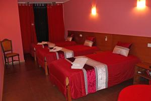 two beds in a hotel room with red walls at Guesthouse Monte Carlo in Porto