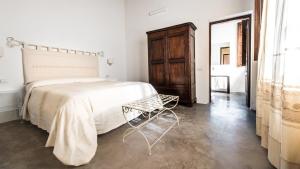a white bedroom with a bed and a wooden cabinet at Faro Capo Spartivento in Chia