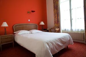 a bedroom with a white bed with an orange wall at Tonic Hôtel du Louvre in Paris
