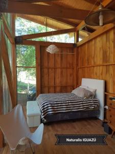 a bedroom with a bed and a chair in it at Casa Naturalis Iguazú in Puerto Iguazú
