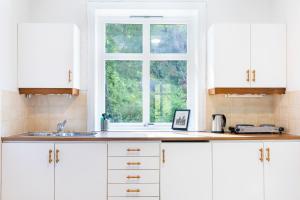 una cocina con armarios blancos y una ventana en Slottet Apartments en Tyssedal