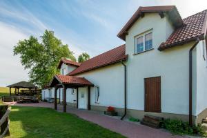 a white house with a porch and a yard at Gospodarstwo Agroturystyczne AGRO-WOLICE in Wolice