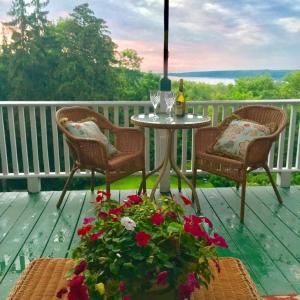a porch with two chairs and a table and flowers at Renwick Clifton House B&B in Saugerties