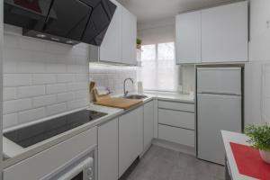 een witte keuken met een wastafel en een koelkast bij Apartamento Avenida de Colón con Aire Acondicionado in Logroño