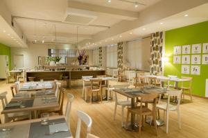 a restaurant with tables and chairs and green walls at Helios Hotel in Monza