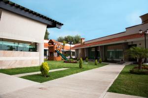 a building with a walkway in front of a yard at Hotel Ecce Inn & Spa in Silao
