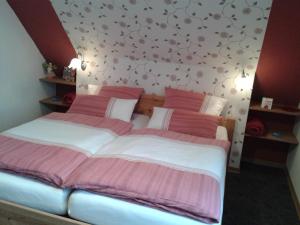 - une chambre dotée d'un grand lit avec des draps roses et blancs dans l'établissement Ferienwohnung Sandhoege, à Börger