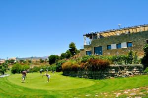 un grupo de personas jugando al golf en un campo de golf en Hostal Loimar, en Torre del Mar