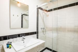 y baño blanco con lavabo y ducha. en Jardin de la Alameda Hostal Boutique, en Sevilla