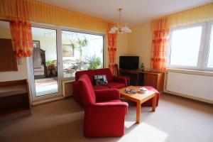 een woonkamer met een rode stoel en een tafel bij Hotel Waldblick in Treffurt