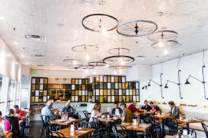 people sitting at tables in a restaurant with clocks on the ceilings at Best Western Plus Palm Court Hotel in Davis