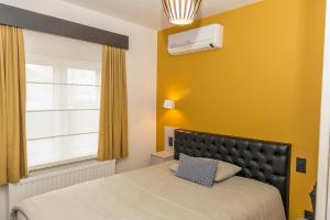 ein Schlafzimmer mit einem Bett und einer gelben Wand in der Unterkunft Belrom Hotel in Sint-Truiden