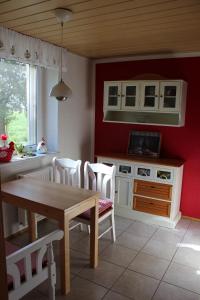 cocina con mesa, sillas y pared roja en Ferienhaus Loose 8 en Letschin