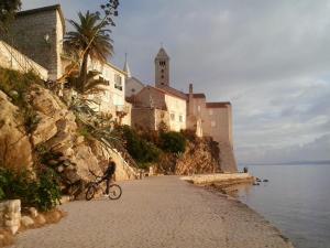 a person riding a bike on a beach next to a castle at apartman Sanja in Rab