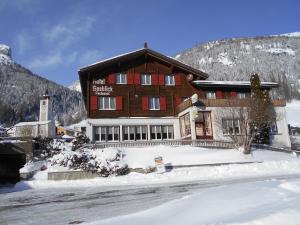 un grand bâtiment en bois avec de la neige au sol dans l'établissement Hotel Seeblick, à Sufers