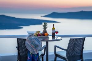 a table with a plate of fruit and a bottle of wine at Asma Suites in Fira