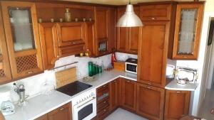 una cocina con armarios de madera y electrodomésticos blancos en Irini's home, en Volos