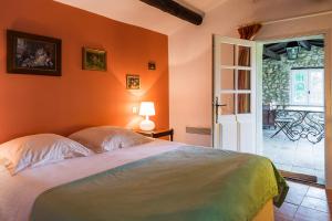 a bedroom with orange walls and a bed and a door at Gites de La Croix du Gres in Valaurie