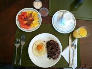 a table with a plate of food with eggs and fruit at Casa del Cafe-Familiar in Heredia