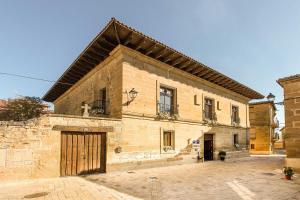 a large brick building with a door in a courtyard at Teatrisso Hotel Palacio in Cuzcurrita-Río Tirón