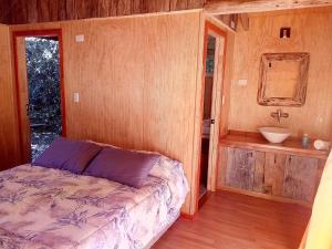 a bedroom with a bed and a bathroom with a sink at Cabañas Sol de Montañas in Futaleufú