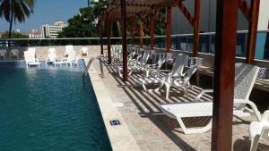 a group of white chairs sitting next to a swimming pool at Apartamentos Cartagena in Cartagena de Indias
