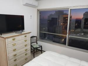 a bedroom with a dresser and a large window at APTO 913 - Piso 9 SANTOS DUMONT Excepcional vista al mar y a la ciudad in Punta del Este