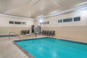 a swimming pool with chairs and tables in a building at Microtel Inn & Suites by Wyndham Springfield in Springfield