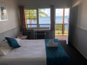 1 dormitorio con 1 cama y vistas al océano en Squid's Ink Motel, en Belmont