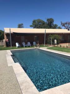 a swimming pool with two chairs and a building at Bridge Motor Inn Tocumwal in Tocumwal