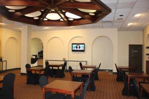 a dining room with tables and chairs and a tv at The Avalon Hotel and Conference Center in Erie