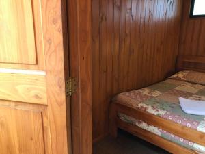 um pequeno quarto com uma cama num chalé de madeira em Hostal el Nogal Pucón em Pucón