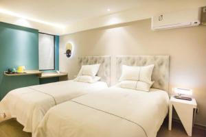 1 Schlafzimmer mit 2 Betten mit weißen Decken und Kissen in der Unterkunft Magnotel Yangshuo West Street in Yangshuo