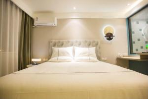 ein Schlafzimmer mit einem großen Bett mit weißen Kissen in der Unterkunft Magnotel Yangshuo West Street in Yangshuo