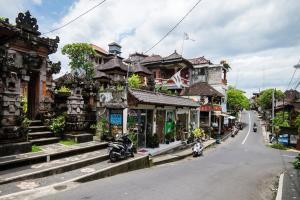 a street with motorcycles parked in front of buildings at Tunjung Guest House in Ubud