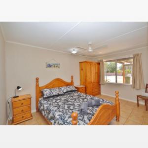 a bedroom with a bed and a desk and a window at Claire’s Place in Kalbarri