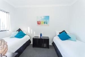 two beds with blue pillows in a room at Bircoo Cottage Beach and Golf Getaway in Bridport