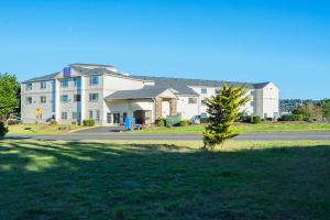 a large white building with a tree in front of it at Motel 6-Newport, OR in Newport