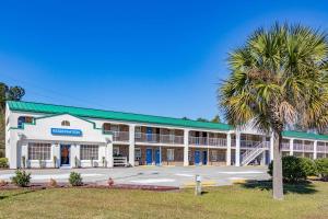 a large building with a palm tree in front of it at Motel 6-Walterboro, SC in Walterboro