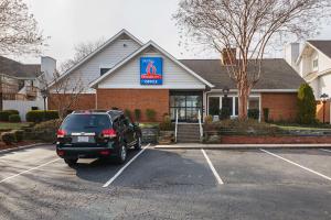 un coche aparcado en un estacionamiento frente a una tienda en Studio 6-Greensboro, NC, en Greensboro