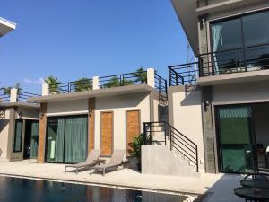 a house with two chairs next to a swimming pool at Baan Fran Sim Da in Bang Tao Beach