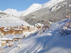 a village covered in snow with mountains in the background at Locations Berne Milesi in Lanslevillard