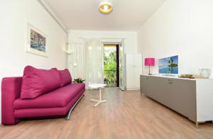 een woonkamer met een paarse bank en een keuken bij Apartments Denise in Podgora